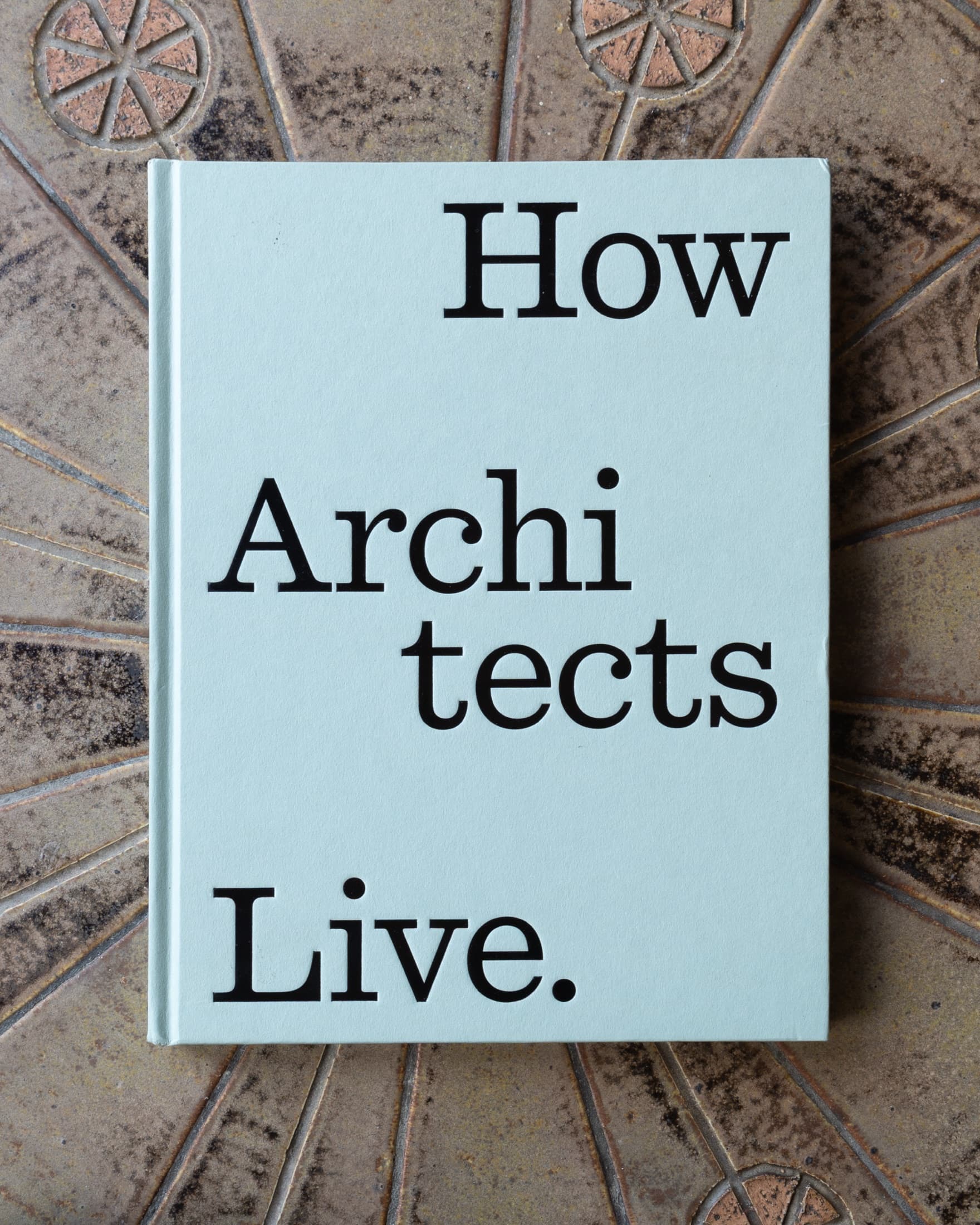 How Architects Live. lying on patterned ceramic tile, sage cloth cover, title in black serif.