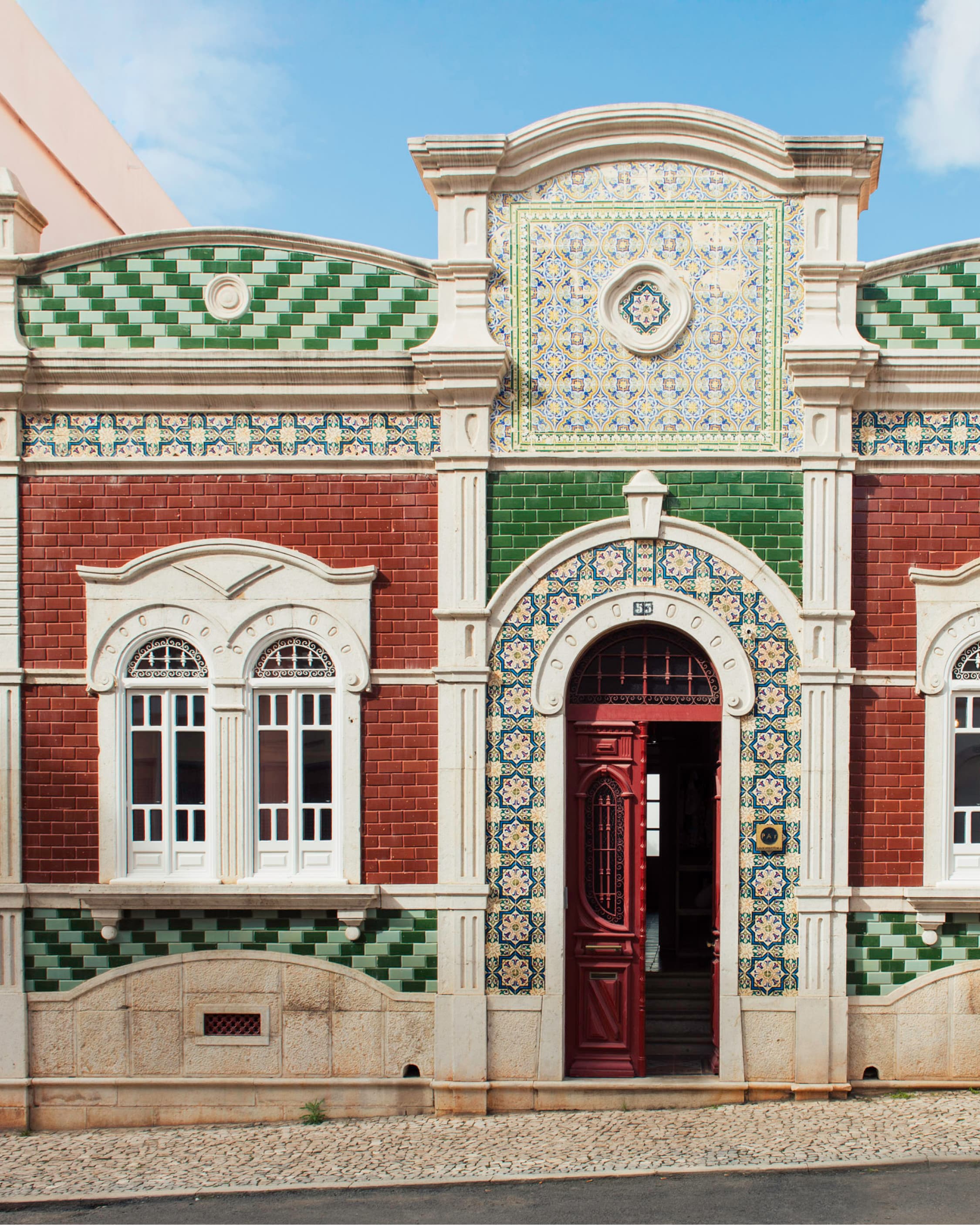 The tiled azulejo façade of Casa 1923, arched shuttered windows, a burgundy door.